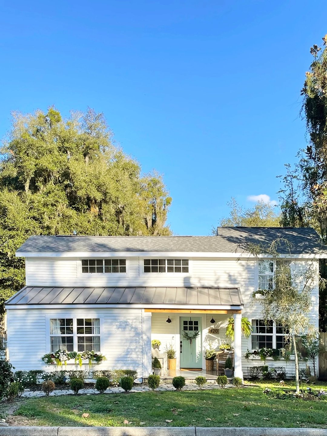 White house exterior with green lawn and mint green door.