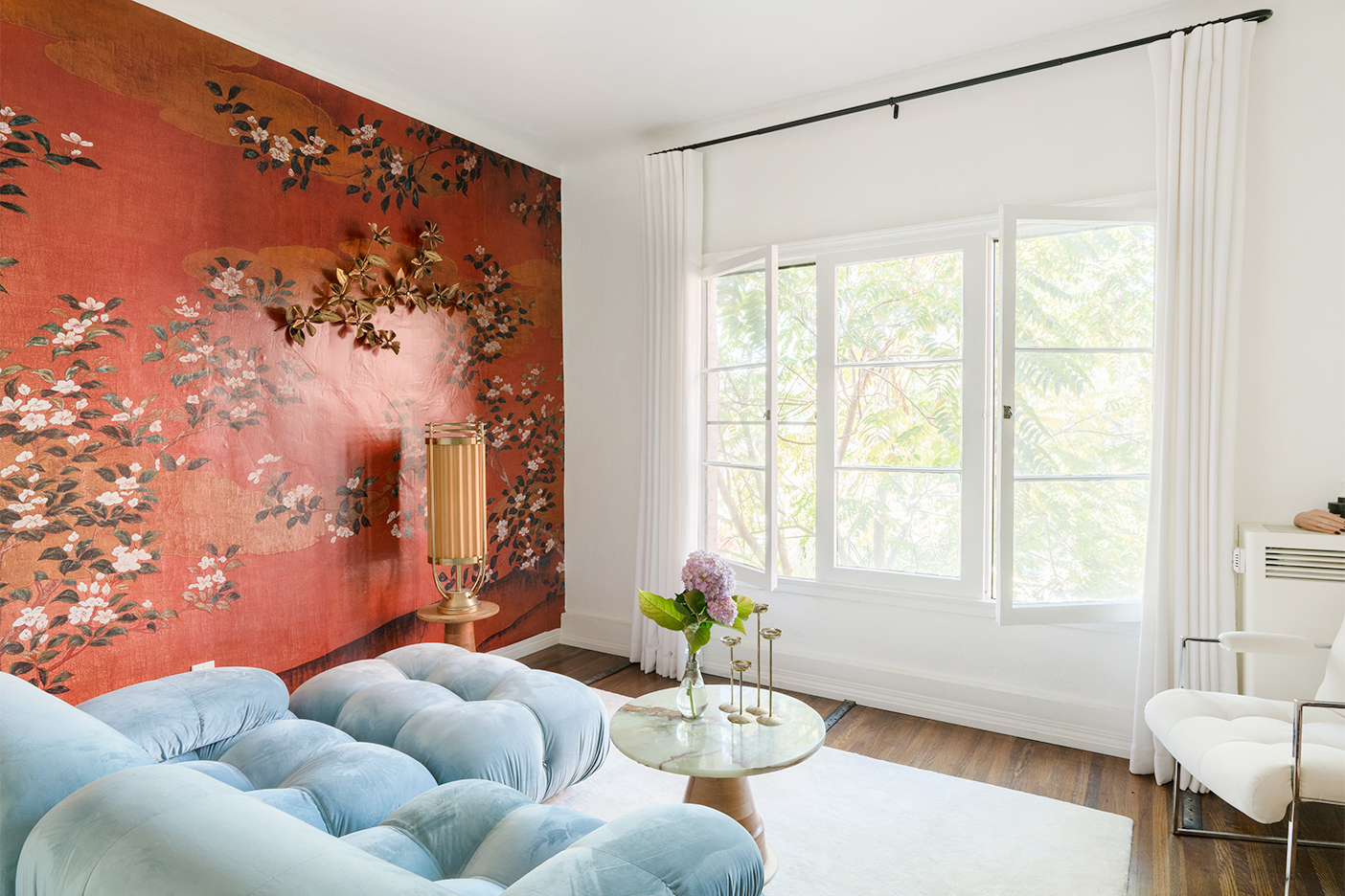 blue sofa in room with red floral wallpaper